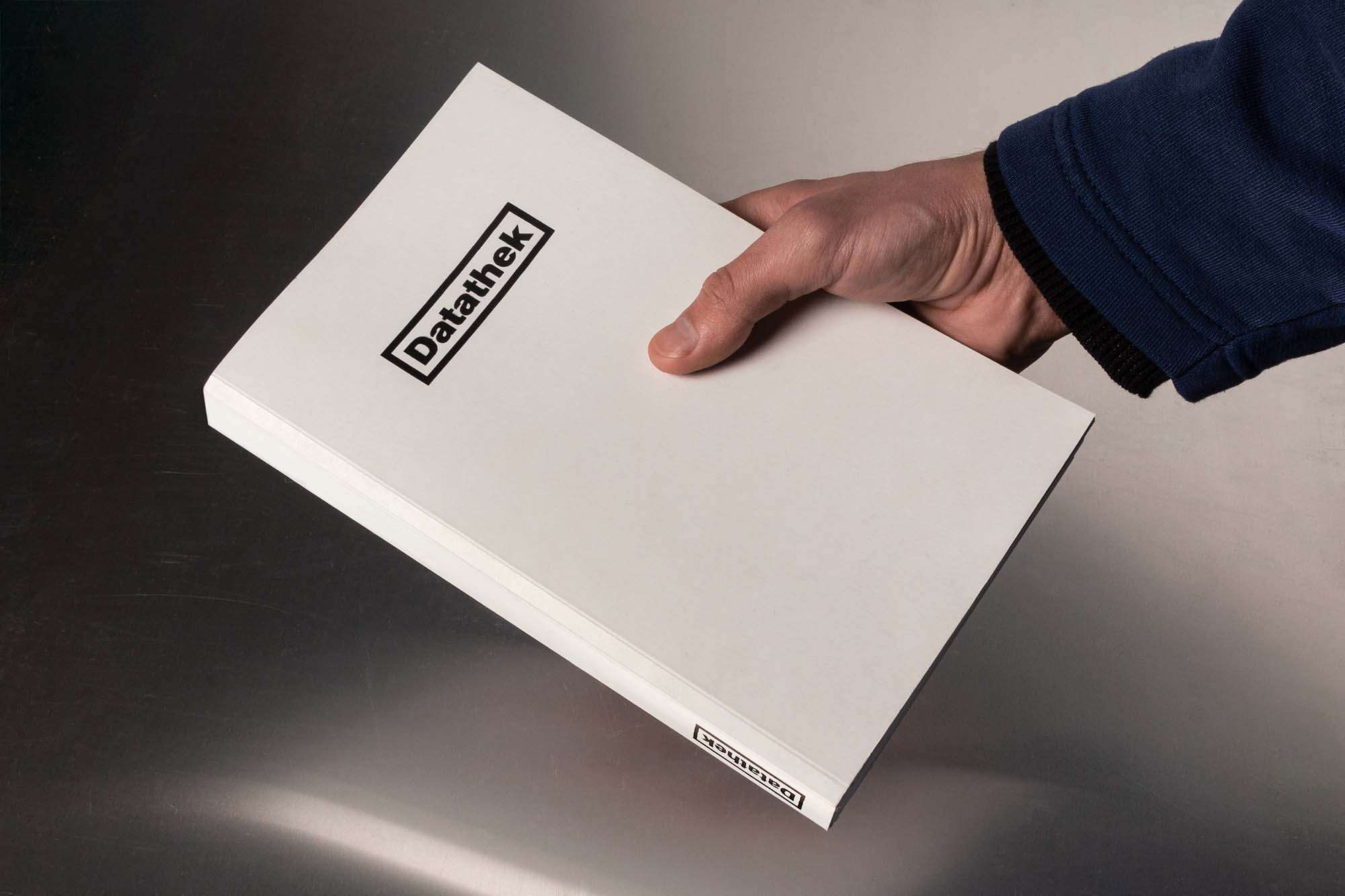 Geschlossenes Buch in einer Hand auf einer Offsetdruckplatte.