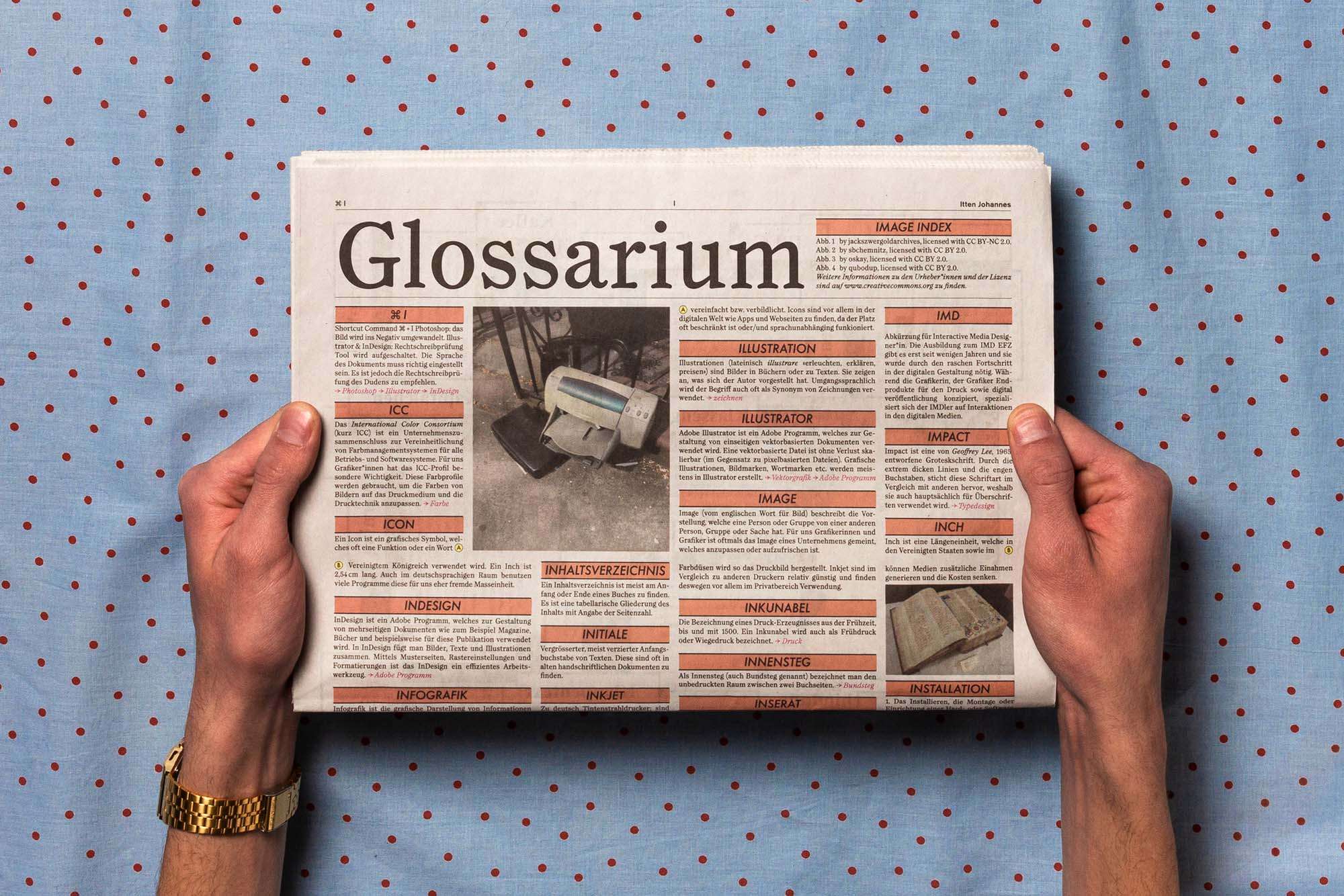 Zeitungsseite halbseitig in den Händen gehalten auf blau/rot gepunktetem Stoff.