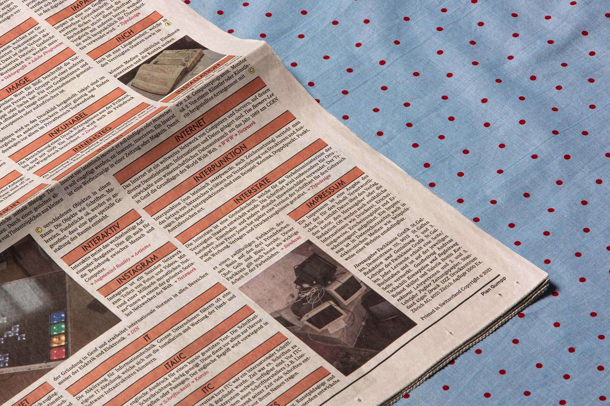 Detailaufnahme der Zeitungsseite auf blau/rot gepunktetem Stoff.