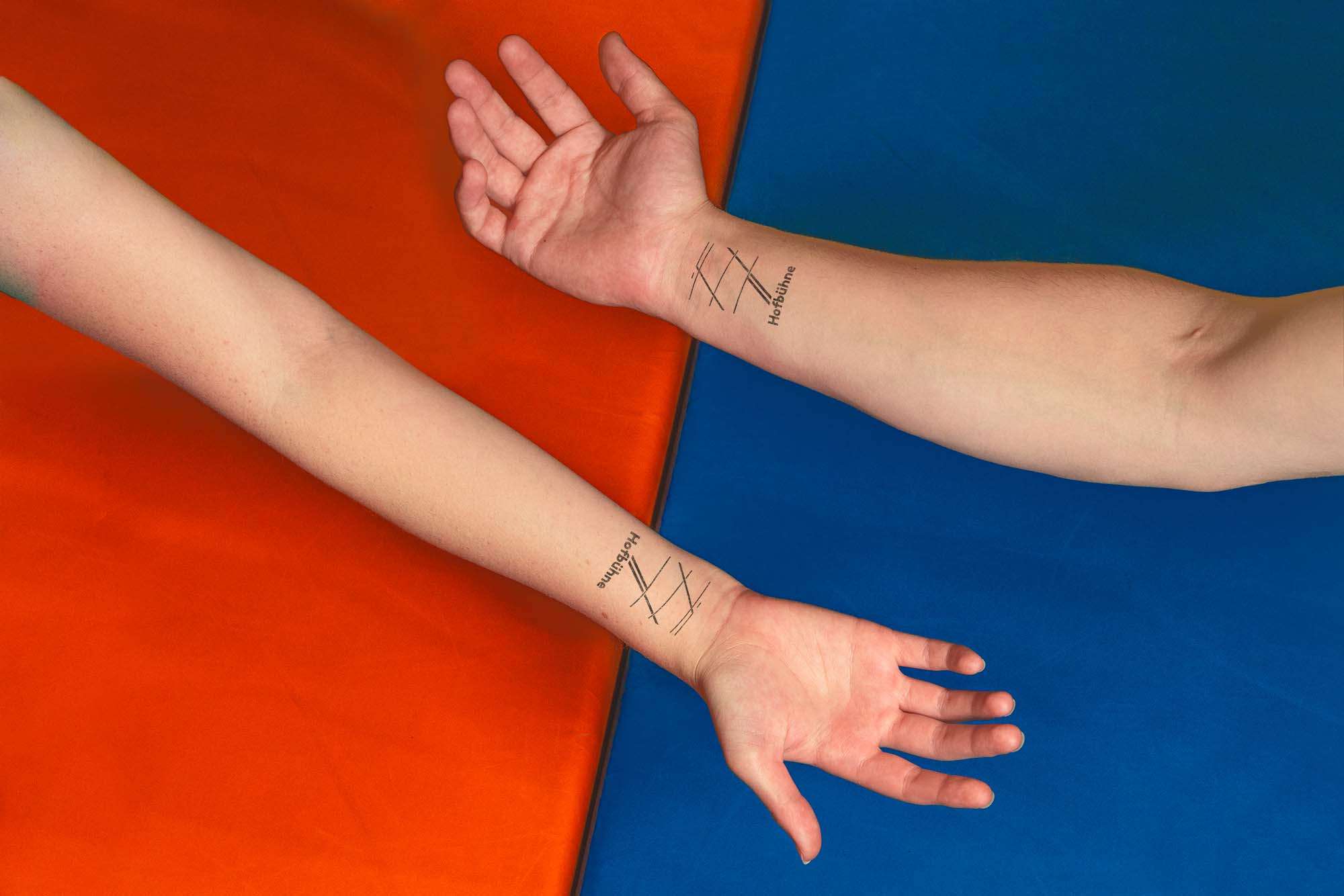 Zwei Hände mit Eintrittsstempel vor zwei Turnmatten.